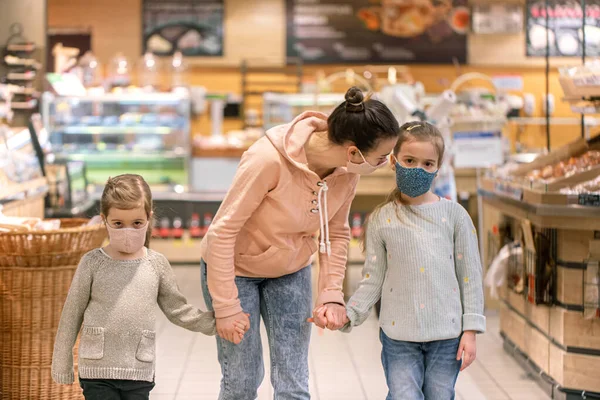 Mom and kids are shopping at the grocery store. They wear masks during quarantine. Coronavirus Pandemic .COVED-19 Flash. The epidemic of the virus