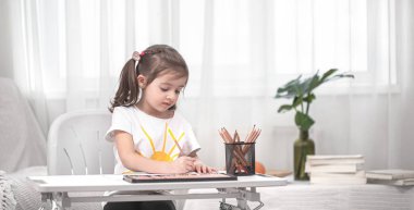 Kız masada oturuyor ve ödev yapıyor. Çocuk evde öğreniyor. Evde eğitim. Metin için boşluk.