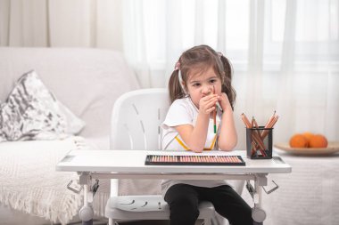 Kız masada oturuyor ve ödev yapıyor. Çocuk evde öğreniyor. Evde eğitim. Metin için boşluk.