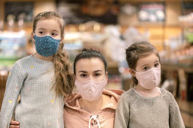 Anne ve çocuklar bakkaldan alışveriş yapıyorlar. Karantina sırasında maske takıyorlar. Coronavirus salgını. 19 Flash. Virüsün salgını.
