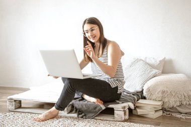 Genç bir kadın evdeki bir bilgisayarın başında uzaktan çalışıyor. Serbest Çalışan ve İnternette Çalışan.