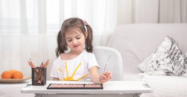 Kız masada oturuyor ve ödev yapıyor. Çocuk evde öğreniyor. Evde eğitim. Metin için boşluk.