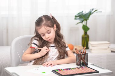 Kız masada oturuyor ve ödev yapıyor. Çocuk evde öğreniyor. Evde eğitim. Metin için boşluk.