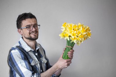 Gözlüklü genç bir adam ve çiçekli bir gömlek. Hafif arka planda. Selamlama ve kadınlar günü kavramı..