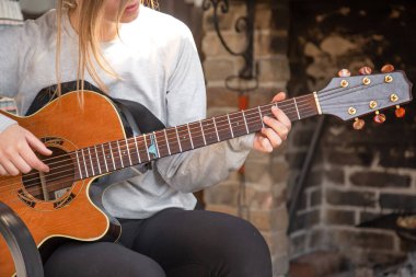 Genç bir kadın rahat bir atmosferde gitar çalar. Hobi ve eğlence kavramı..