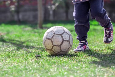 Çocuklar çimenlerde futbol oynarlar, ayaklarını topta tutarlar. Takım oyunu konsepti.