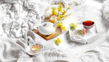 Bir fincan çay ve çiçeklerle bahar hayat doludur. Açık arkaplan, çiçek açan ve rahat ev.