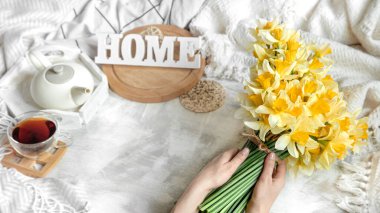 Bir fincan çay ve çiçeklerle bahar hayat doludur. Açık arkaplan, çiçek açan ve rahat ev.