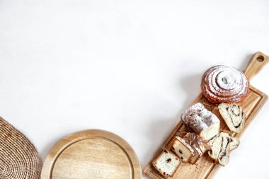 Tahta bir çubukta farklı taze hamur işleri kesilir. Hafif bir arkaplanda, metin için boşluk.