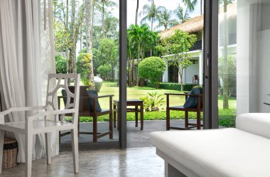 Odanın içinde güzel ahşap bir sandalye ve terasa ve bahçeye erişim..