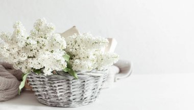 Hasır sepette leylak çiçekleri olan bahar kompozisyonu. Anneler ve kadınlar günü. Mesaj için yer var. Yatay oryantasyon. Hediye sepetleri ve çiçek teslimatları.