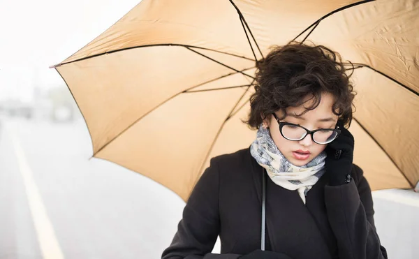 Chica en gafas de pie bajo el paraguas — Foto de Stock