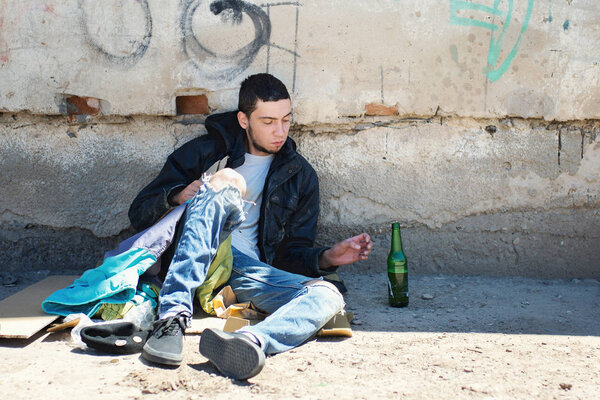 Бездомный сидит на земле
