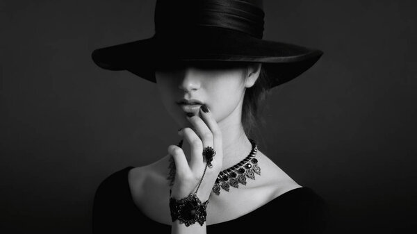 Monochrome portrait of young woman in black clothes and hat 