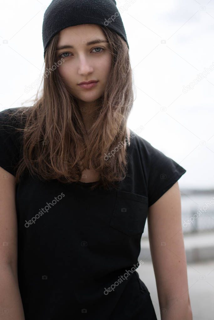 Beautiful teenage girl in black shirt and hat posing outdoors