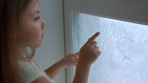 Kind trekt een vinger op het vensterglas — Stockvideo