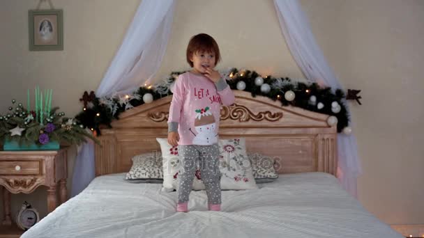 Szczęśliwa dziewczynka w piżamy leżąc na łóżku — Wideo stockowe