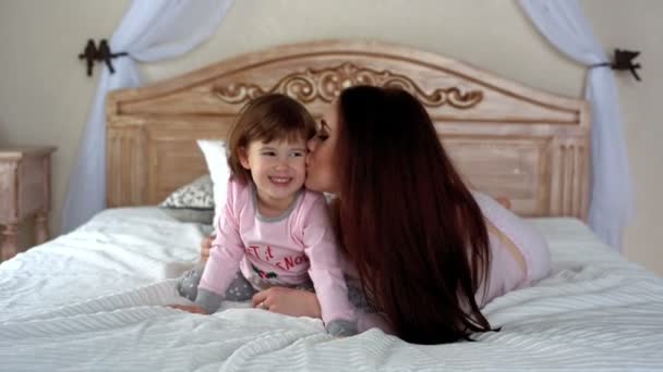 Mutlu genç anne ve kızı yatakta sarılma — Stok video