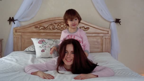 Feliz joven madre e hija abrazándose en la cama — Vídeos de Stock