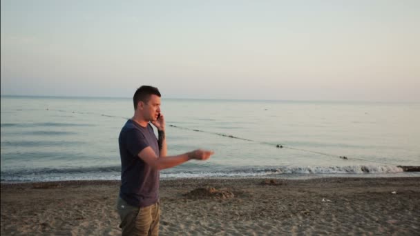 Junger Mann telefoniert am Strand — Stockvideo