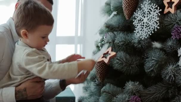 En liten pojke dekorerar en julgran — Stockvideo