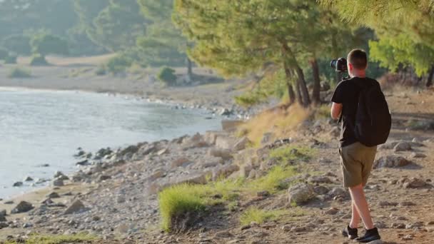 Ένας ταξιδιώτης πυροβολεί βίντεο πλάνα από ένα υπέροχο ηλιοβασίλεμα στην ακτή της μια ορεινή λίμνη — Αρχείο Βίντεο