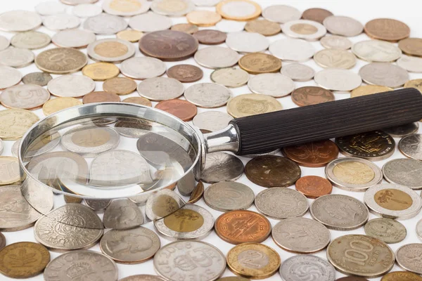 Different collector's coins and magnifying glass — Stock Photo, Image