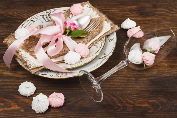 Rose rosa chiaro e stoviglie sulla tavola di legno — Foto Stock