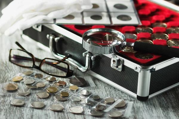 Коробка з колекційними монетами, збільшуючи скло і окуляри — стокове фото