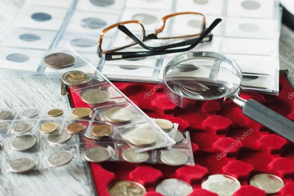Different collector's coins with a magnifying glass and glasses