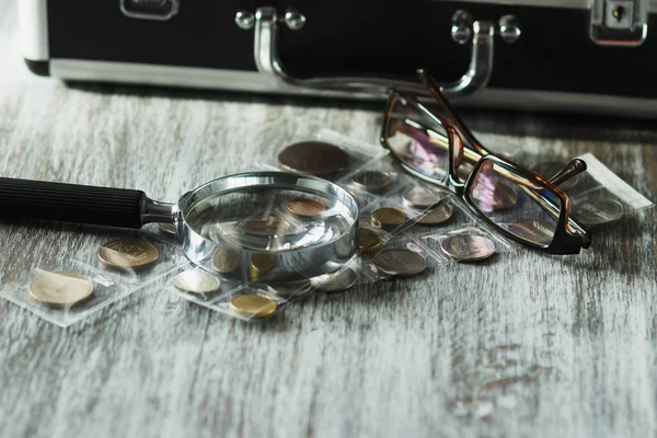 Колекційні монети, збільшуючи скло і окуляри, м'який фон фокусу — стокове фото