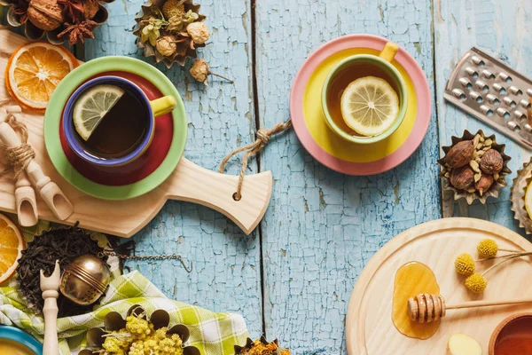 Tazas con té de hierbas y trozos de limón, hierbas secas y diferentes decoraciones —  Fotos de Stock