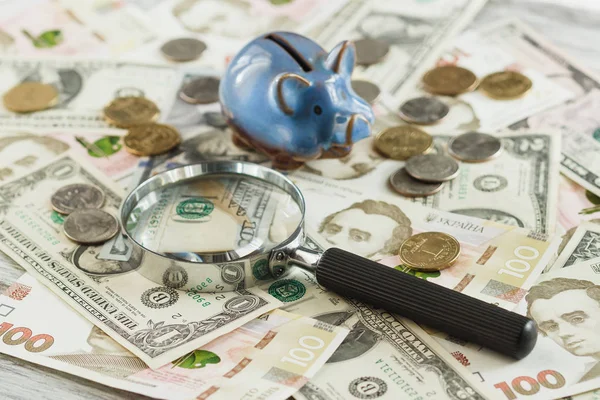 Ukraynalı hryvnia ve Amerikan dolar bir kumbara ve Büyüteç ile — Stok fotoğraf