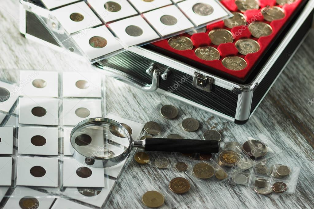 Different collector's coins in the box for coins and a magnifying glass