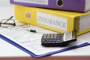 Temiz sigorta formu, klasör, kalem, gözlük ve hesap makinesi