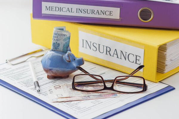 Clean insurance form, folders, pen, piggy bank and glasses