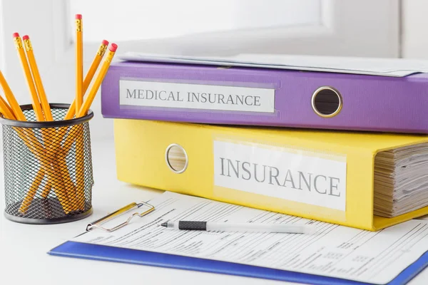 Ren-blanketten för sjukförsäkring, mappar, pennor i hållaren och penna — Stockfoto