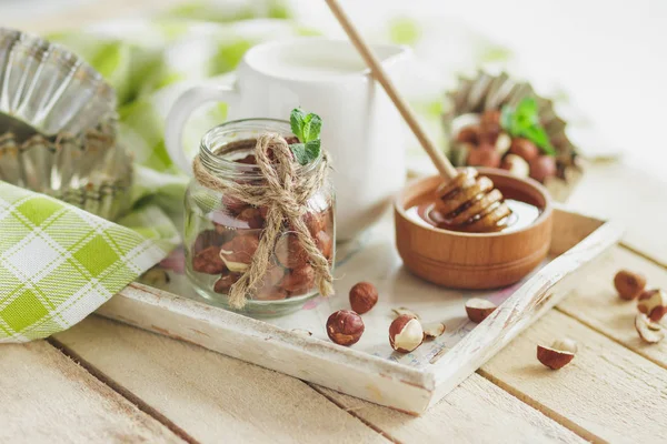 Honung i trä bowl, mynta blad, hasselnötter och burk med mjölk — Stockfoto