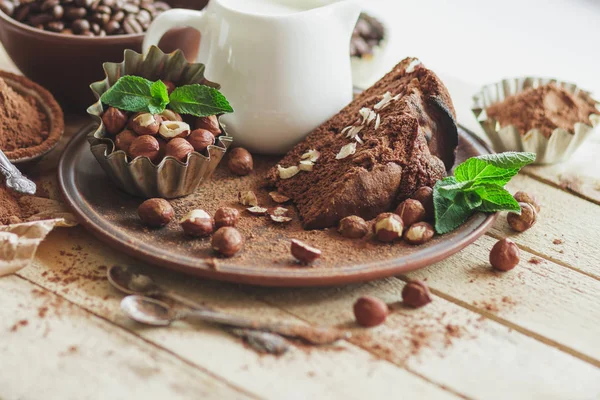 Bit chokladkaka, myntablad, hasselnötter och burk med mjölk — Stockfoto