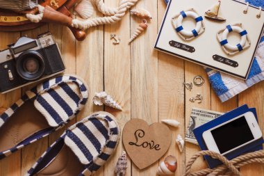 Çizgili terlik, fotoğraf makinesi, telefon ve deniz süslemeleri, üstten görünüm