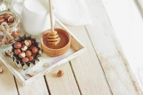 Honung i trä skålen, hasselnötter och burk med mjölk i trä facket — Stockfoto
