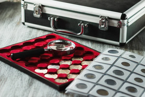 Different collector's coins in the box for coins and a magnifying glass — Stock Photo, Image