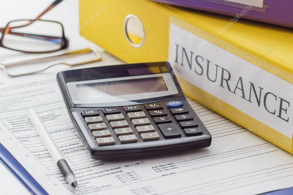 Clean insurance form, folders, pen, glasses and calculator