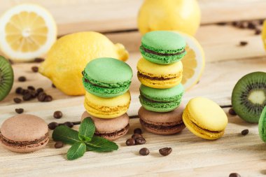 Yeşil, sarı ve kahverengi macarons kivi kahve çekirdekleri ve nane süslemeleri ile