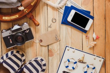 Çizgili terlik, fotoğraf makinesi, telefon ve deniz süslemeleri, üstten görünüm