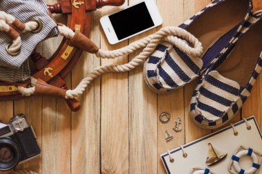 Çizgili terlik, fotoğraf makinesi, telefon ve deniz süslemeleri, üstten görünüm