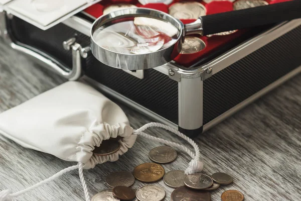 Different collector's coins with a magnifying glass and money bag — Stock Photo, Image