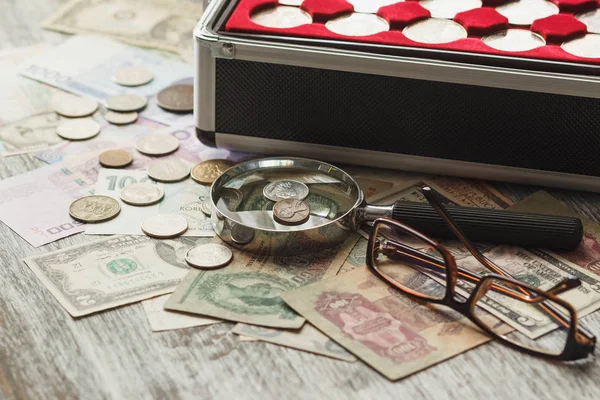 Різні колекційні монети та банкноти зі збільшувальним склом — стокове фото