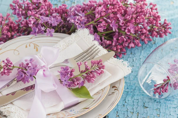 Louça e talheres com lilás violeta sobre o fundo de madeira — Fotografia de Stock