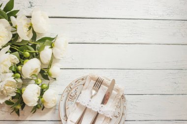 Sofra ve gümüş beyaz ahşap kurullarında beyaz peonies bir buket